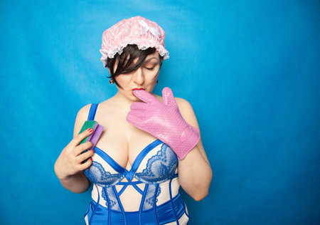 adorable happy plus size short hair woman in blue white lingerie with a rubber glove and a sponge...