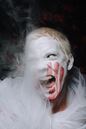 halloween make up. scary man ready for party. guy with face covered in white paint and bloody...