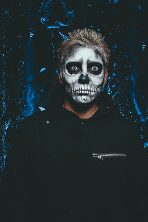 halloween make up. scary man ready for party. scary strange man with a painted skull on his face on...
