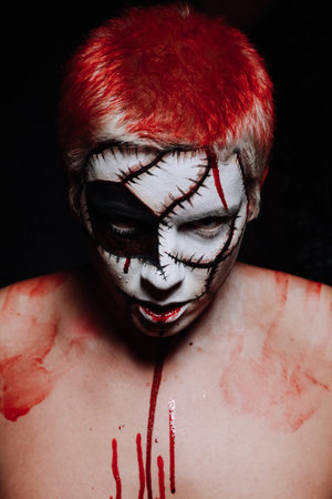 halloween make up. scary man ready for party. strange man portrays dead bloody clown on black...
