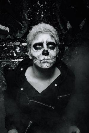 halloween make up. scary man ready for party. strange male with skull painted on his face in black...