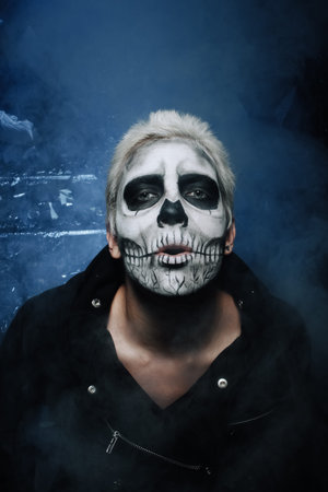 halloween make up. scary man ready for party. strange male with skull painted on his face in black...