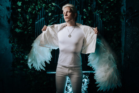 A portrait of a man with big feathered wings against a dark background.の写真素材