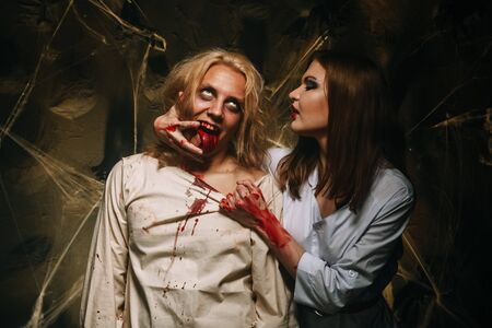 Portrait of a beautiful couple in medical bloody costumes with halloween style make-up. Shot in a studio.の写真素材