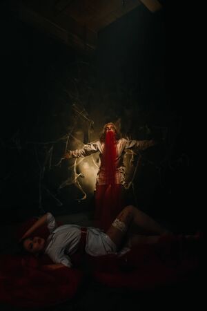 crazed lunatic in a straitjacket vomiting red fabric, and underneath lies a cute doctorの写真素材