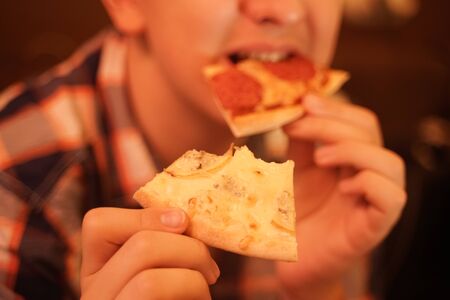 teen boy eats pizza and enjoys it, closeup enjoying and savoringの写真素材