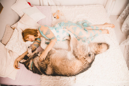 charming plus size girl with red hair in a nightgown posing with her large dog, a Malamute best...