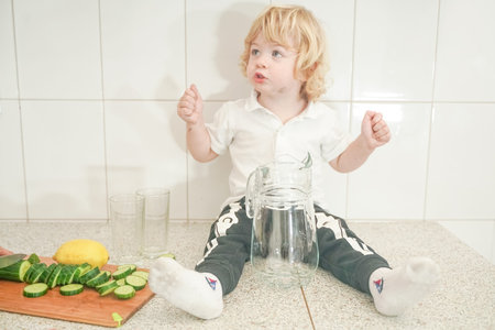 Portrait of an adorable mother and little baby child preparing a vegetable water drink together in the white kitchenの写真素材