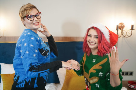 pretty girl gives her friend a present wedding ring on christmas. happy woman lovely couple.の写真素材
