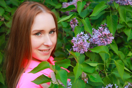 beautiful young teen girl standing in the flowers of lilac