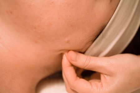 Beautiful young woman getting a face massage treatment at beauty salon.の写真素材
