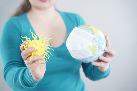 Global Flu Pandemic Concept. Female arms with world globe With Medical Mask against covid-19...