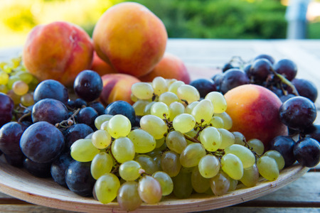 peaches and grapes in a plate on the tableの写真素材