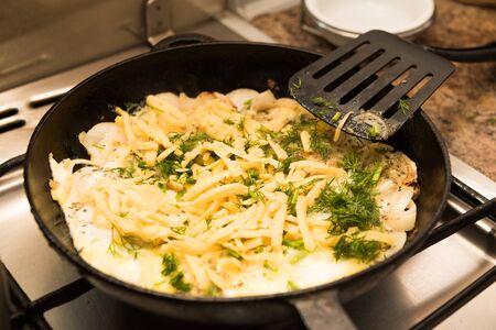 cooking eggs with cheese and herbsの写真素材