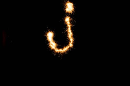English alphabet from yellow sparkler on black backgroundの写真素材