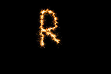 English alphabet from yellow sparkler on black backgroundの写真素材
