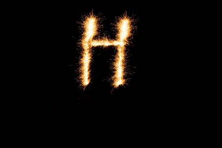 English alphabet from yellow sparkler on black backgroundの写真素材