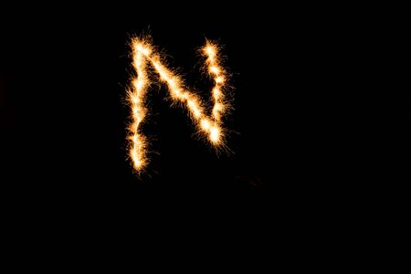 English alphabet from yellow sparkler on black backgroundの写真素材