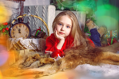 The girl is a child with long thick hair, looking into the camera. A girl in a red Christmas sweater. New Year's card. Selective focus. Backgroundの写真素材