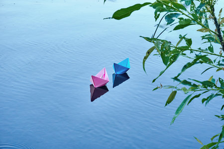 Two boats of blue and pink color, swim on the river. Summer day, rest on the pond