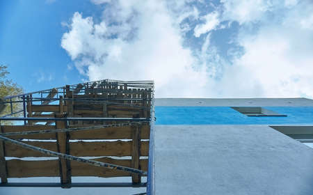Scaffolding for repair and construction. Built scaffolding in the share of the repaired wall of the building. Against the background are white clouds and blue sky.の写真素材