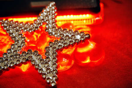 A silver textured star lies on red velvet strewn with glass red hearts. selective focus.の写真素材