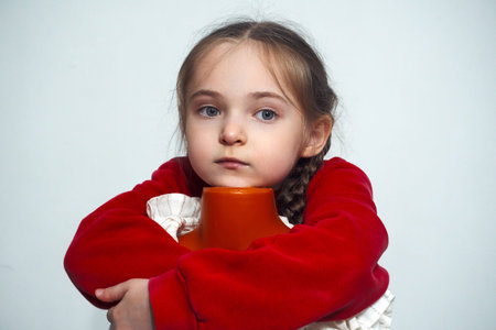 A girl with pigtails hugs a mannequin and looks at the camera. A girl in a red sweater. selective focus.の写真素材