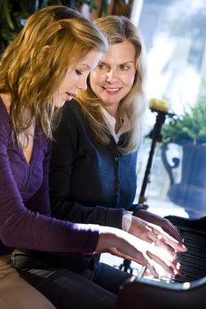 Portrait of mother and teen daughter sitting at grand pianoの写真素材