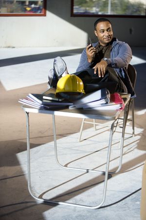 Worker in unfinished office space with feet up on folding tableの写真素材