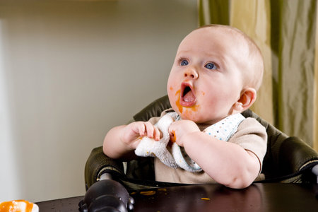 Cute hungry six month old baby eating solid food