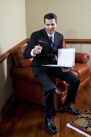 Businessman sitting on couch looking up with notebook in hand, conversingの写真素材