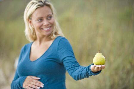 Pregnant woman holding pear, focus on pearの写真素材