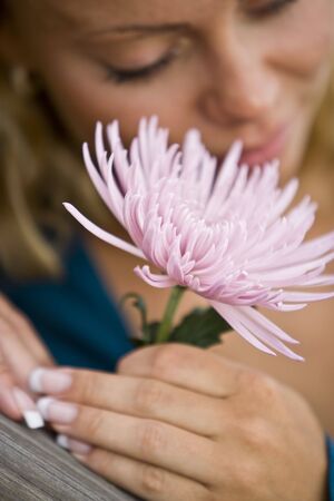 Close-up of beautiful flower by face of young woman, focus on flowerの写真素材