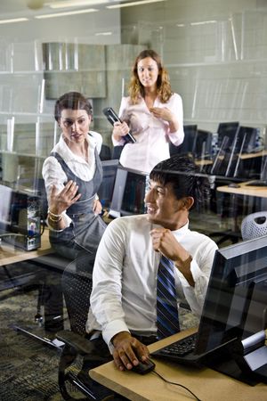 Three university students conversing in library computer roomの写真素材
