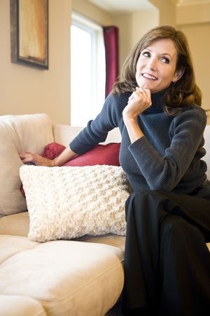 Attractive mature woman relaxing on couch in elegant modern living roomの写真素材