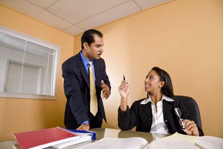 Young African-American female office worker talking with middle-aged Hispanic colleague in boardroomの写真素材