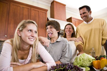 Happy family with two teenage children making funny faces in kitchenの写真素材
