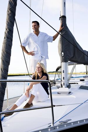 Father and teenage daughter smiling on sailboat at dock on sunny dayの写真素材