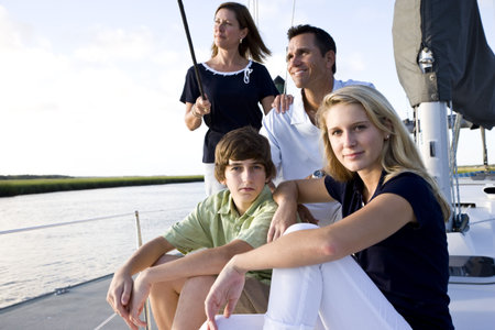 Family with teenage children sitting on boat at dock on sunny dayの写真素材