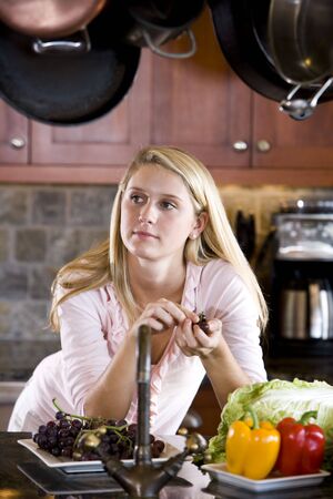 Pretty 17 year old teenage girl leaning on kitchen counter thinkingの写真素材