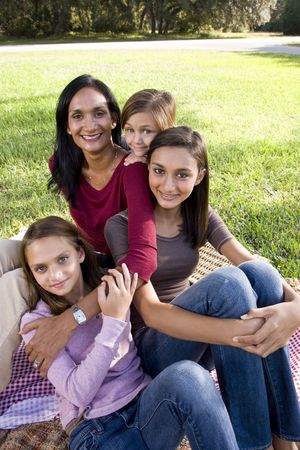 Indian mother and three children enjoying family picnic in park on sunny dayの写真素材