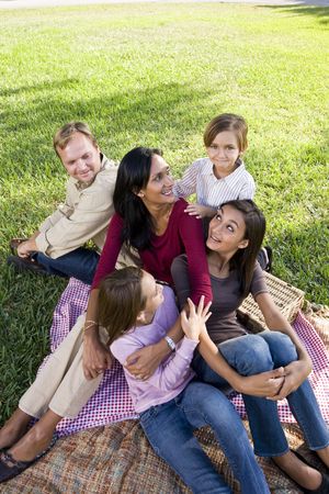 Interracial family with three children having picnic in parkの写真素材