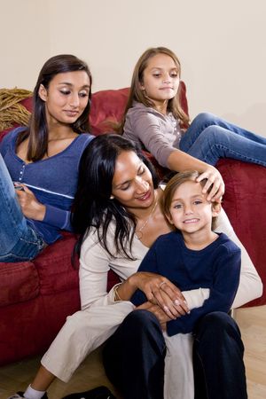 Family portrait of Indian mother with 3 mixed-race children sitting at home together on sofaの写真素材