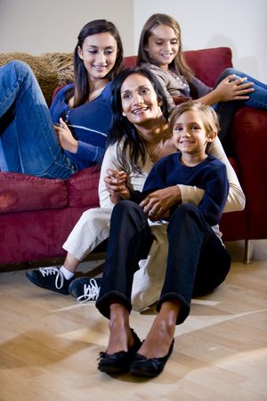 Indian mother with three mixed-race children relaxing on living room sofaの写真素材