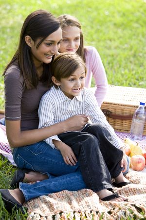 Teenage girl and two younger siblings enjoying picnicの写真素材