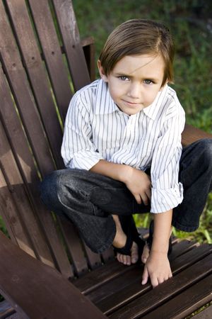 Portrait of a cute little 5 year old boy on an adirondack chairの写真素材