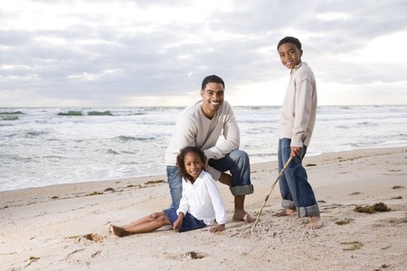 Happy African-American father and two children together on beachの写真素材