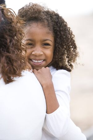 Close-up of cute six year old African-American girl in mother's armsの写真素材