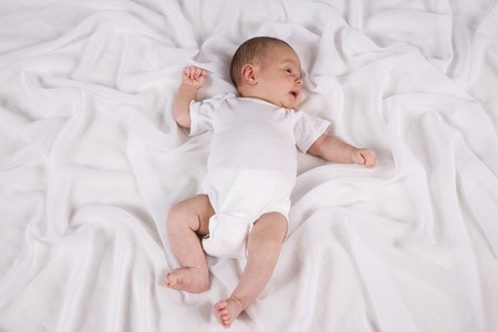 One month old newborn baby boy lying on white blanketの写真素材