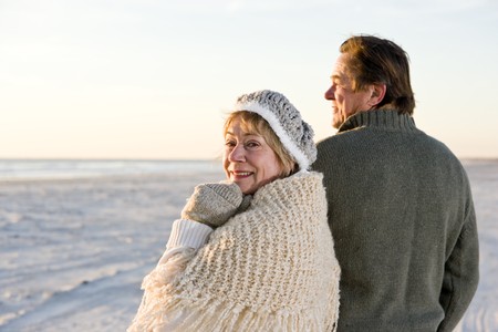 Affectionate senior couple in sweaters together on beach の写真素材